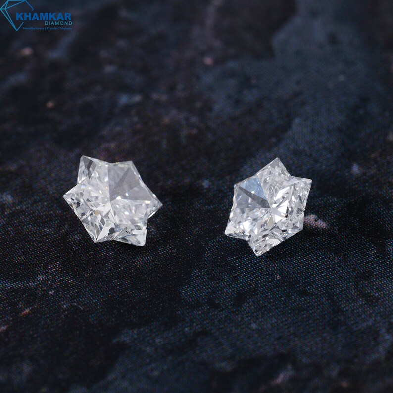 May include: Two clear, faceted, star-shaped diamonds on a black background.