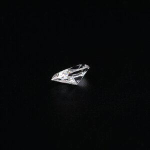 May include: A clear, round, faceted diamond gemstone on a black background.