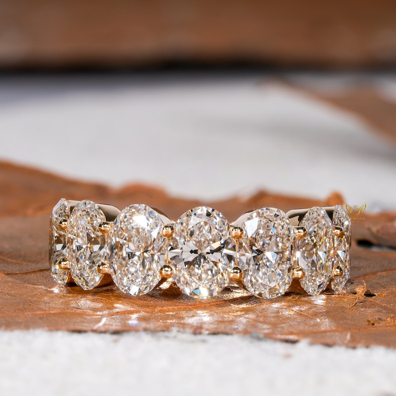 May include: A gold band ring with five oval-shaped diamonds set in a pave setting.