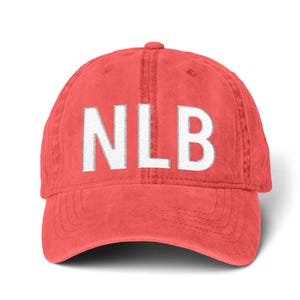 Puede incluir: Gorra de béisbol de color coral con las letras blancas bordadas "NLB" en la parte delantera. La gorra tiene una visera curva y un cierre de correa de tela en la parte trasera. Hecha de un material suave y texturizado.