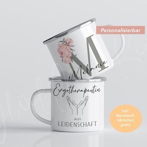 May include: Two white enamel mugs with black lettering. The top mug has a floral design and the text "M Melanie". The bottom mug has the text "Engotherapeutin aus LEIDENSCHAFT" and a graphic of two hands with palms facing up. The text "Personalisierbar" is in the top right corner of the image. The text "Inkl. Baumwoll-S&auml;ckchen gratis" is in the bottom right corner of the image.