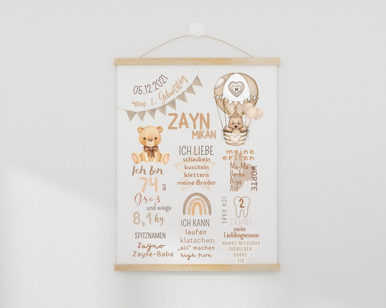 May include: A beige and brown illustrated baby milestone poster with a hot air balloon, teddy bears, and rainbows. The poster features the name "Zayn Mikan" and details about the baby's first year, including their height, weight, first words, and favorite foods.