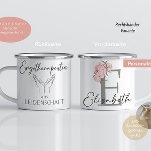 May include: Two white enamel mugs with silver rims. The mug on the left has black text that reads "Ergotherapeutin aus LEIDENSCHAFT". The mug on the right has a floral design with pink flowers and gray text that reads "Elisabeth".