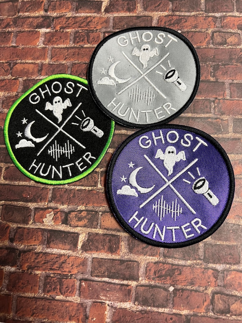 May include: Three embroidered patches with the text "Ghost Hunter" in white lettering on a black, grey, and purple background. Each patch features a white ghost, crescent moon, and flashlight.