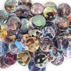 May include: A collection of round, glossy buttons featuring various cartoon characters. The buttons display colorful illustrations of characters in a variety of scenes. The buttons are scattered across a white surface.