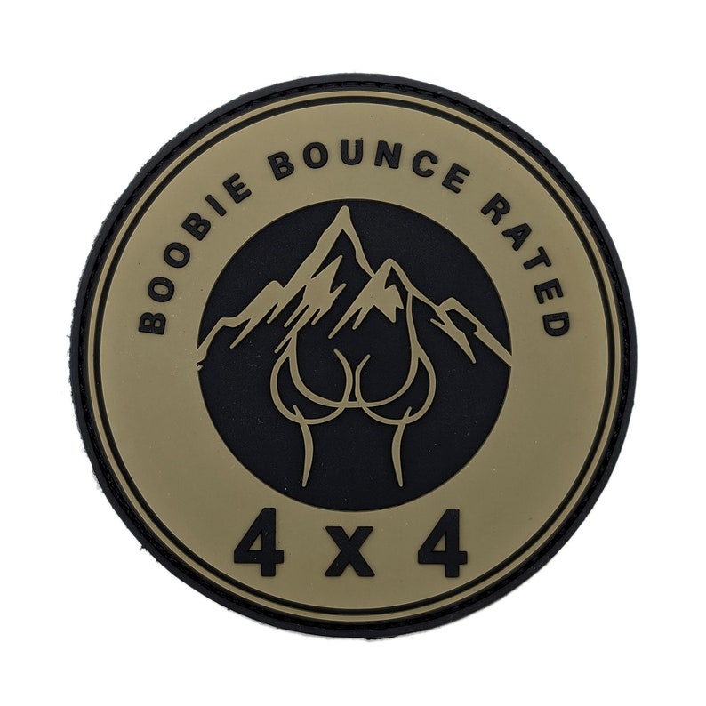 May include: A round patch with a black border and a tan center. The text "BOOBIE BOUNCE RATED" arcs around the top. A mountain range and a stylized image of breasts are in the center. The text "4 X 4" is at the bottom.