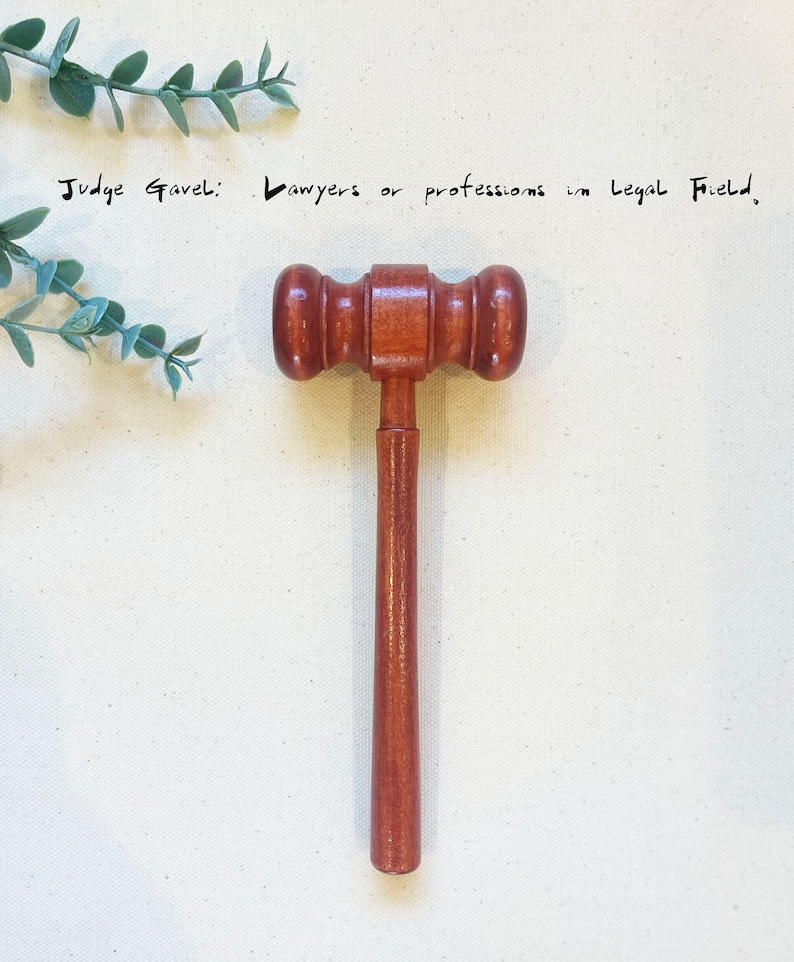 May include: A wooden judge's gavel with a brown handle. The gavel is a symbol of authority and justice, often used in courtrooms and legal proceedings. "Judge Gavel: Lawyers or professions in legal field."