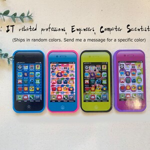 May include: Four toy cell phones in different colors: blue, pink, yellow, and purple. Each phone has a screen with icons for apps like clock, calendar, weather, games, music, and more. The text on the phones reads "Phome: IT related professions Engineers Computer Scientists, etc (Ships in random colors. Send me a message for a specific color)"