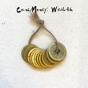 May include: A string of ten gold-colored Chinese coins tied together with twine. The coins have Chinese characters on them and are a symbol of wealth and good fortune.