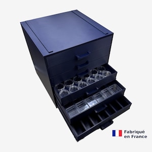 Peut inclure: Un meuble de rangement bleu foncé à tiroirs multiples, contenant des récipients circulaires transparents dans un tiroir et des compartiments carrés transparents dans un autre. Le tiroir inférieur possède des séparateurs. Texte Fabriqué en France.