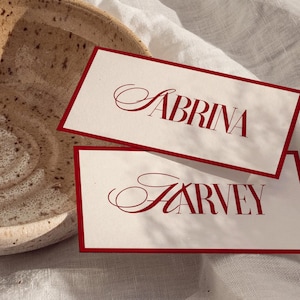 Elegantes tarjetas de lugar para bodas con nombres de invitados Plantilla de tarjeta de lugar plana Nombres de lugares en forma de carpa con borde rojo - Sabrina