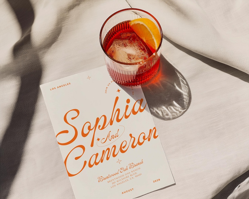 May include: A white wedding invitation with orange text announcing the wedding of Sophia and Cameron. The invitation includes the date, location, and venue: Brentwood Oak Branch, Brentwood, CA, August 2028.