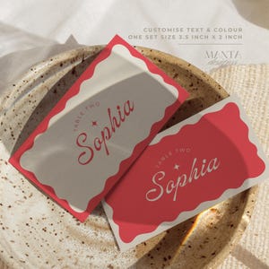 May include: Two rectangular place cards measuring 3.5 inches by 2 inches. One card features a red scalloped border on a beige background, the other a beige scalloped border on a red background. Both display the text 'TABLE TWO' and 'Sophia'.