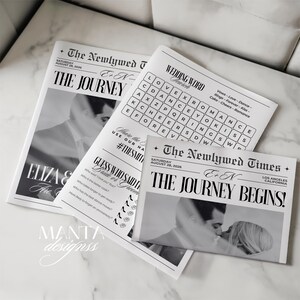 May include: A collection of black and white wedding stationery designed to look like newspapers. The headlines read "The Journey Begins!" and include a word search and a "Guess Who Said" game. The date "August 28, 2026" is printed on the newspapers.