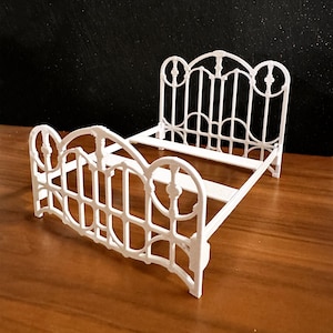 Puede incluir: Estructura de cama de metal blanco con un diseño decorativo. El marco está hecho de barras de metal delgadas y tiene un estilo simple y elegante.