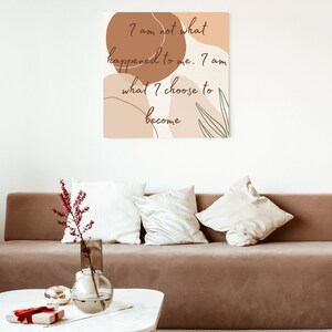 May include: A motivational quote on a canvas print with an abstract background of brown and beige shapes and green leaves. The quote reads "I am not what happened to me. I am what I choose to become."