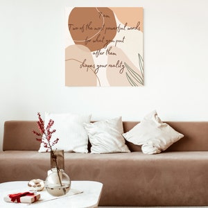 May include: A beige and brown abstract art print with a quote that reads "Two of the most powerful words for what you put after them shapes your reality."