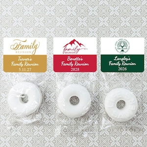 May include: Three white round mints in clear plastic bags with personalized labels. The labels are gold, red, and green with the text "Family Reunion" and the names of the families, dates, and years.