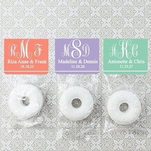 May include: Three favor bags with white mints and personalized labels. The labels are in coral, lavender, and mint green with white lettering. The labels include the couples' names and wedding dates.