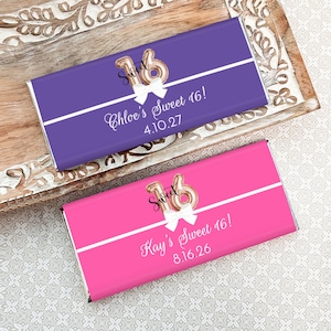 May include: Two chocolate bar wrappers, one purple and one pink, with "Sweet 16" designs. Each wrapper features a gold balloon "16", a white bow, and personalized text. The purple wrapper says "Chloe's Sweet 16! 4.10.27", and the pink one says "Kay's Sweet 16! 8.16.26".