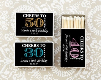 Könnte beinhalten: Drei schwarze Streichholzschachteln mit weißen Rändern. Jede Schachtel hat eine andere Farbe für die Zahl und den Text. Die erste Schachtel sagt "Cheers to 50 Years" mit einer goldenen 50. Die zweite Schachtel sagt "Cheers to 30 Years" mit einer türkisfarbenen 30. Die dritte Schachtel sagt "Cheers to 40 Years" mit einer rosafarbenen 40.