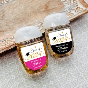 May include: Two clear plastic bottles of hand sanitizer with graduation themed labels. The labels are white with black text and gold stars. One label says "Class of 2024" with a black graduation cap and the name "Matthew" and the date "6.21.20XX". The other label says "Class of 2024" with a black graduation cap and the name "Valerie" and the date "6.14.20XX".
