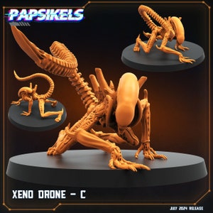 May include: A 3D printed, orange-brown, articulated Xenomorph drone figure in a crouching pose. The figure has a long, segmented tail and a large, rounded head with a mouth that opens to reveal rows of sharp teeth. The figure is posed on a black circular base. The text "XENO DRONE - C" is printed on the base. The text "PAPSIKELS" is printed in a retro, pixelated font at the top of the image. The text "JULY 2024 RELEASE" is printed at the bottom of the image.