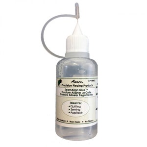 May include: A clear plastic bottle of SeamAlign Glue by Acorn Precision Piecing Products. The bottle has a white cap and a green label with the product name and instructions. The label also states that the glue is ideal for quilting, sewing, and appliqué. The bottle is non-toxic.