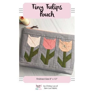 May include: A gray zippered pouch with a quilted design featuring three stylized tulips in white, pink, and orange. The pouch is 8 inches by 12 inches and has the text "Tiny Tulips Pouch" and "Finished Size 8" x 12" ".