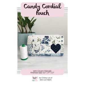 May include: A blue and white patchwork fabric pouch with a black heart detail. The pouch is 4.5 inches wide, 9 inches long, and 3 inches deep. The pouch is labeled "Candy Cordial Pouch" and is mini charm friendly.
