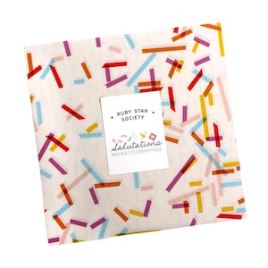 May include: A square fabric piece with a white background, adorned with colorful, scattered rectangular shapes in red, orange, yellow, purple, and blue. A small card with the text "RUBY STAR SOCIETY" and "salutations" is placed on top.