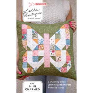 May include: A green quilted pillow with a butterfly design made of patchwork squares in various colors. The pillow has a pink center stripe and the text "#249 MINI CHARMED" and "a charming pillow (or mini quilt) emerges from the scraps".