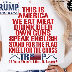 May include: A white t-shirt with red text that reads "Trump America is Back" and "This is America We Eat Meat Drink Beer Own Guns Speak English Stand for the Flag Kneel for the Cross" with a red, white, and blue American flag and crossed rifles. The text "Trump" is in a red box with stars above it. The text "If You Don't Like It Leave!" is below the flag and rifles.