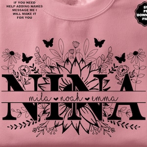 Könnte beinhalten: Ein rosa Sweatshirt mit einem schwarzen Blumendesign und dem Wort "NINA" mit den Namen "mila", "noah" und "emma" darunter. Der Text "SVG PNG DOWNLOAD FILES" befindet sich in der oberen rechten Ecke.