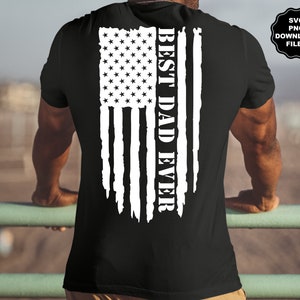 K&ouml;nnte beinhalten: Ein schwarzes T-Shirt mit einem wei&szlig;en, abgenutzten amerikanischen Flaggenmuster und dem Text "BEST DAD EVER", der vertikal auf der R&uuml;ckseite aufgedruckt ist.