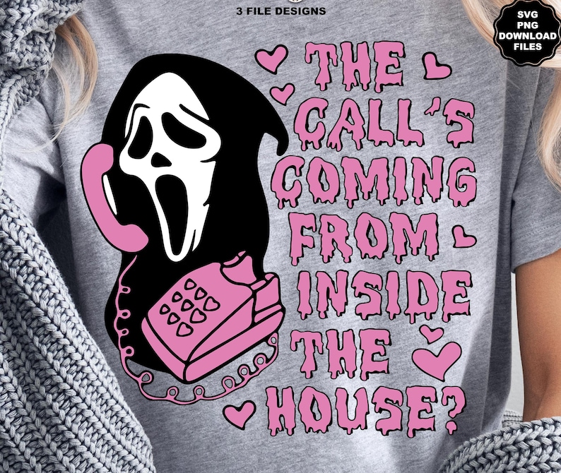 Puede incluir: Una camiseta gris con un gr&aacute;fico de una m&aacute;scara de Ghostface sosteniendo un tel&eacute;fono rosa. El texto "THE CALL'S COMING FROM INSIDE THE HOUSE?" est&aacute; en rosa, con corazones. Incluye archivos de descarga SVG y PNG.
