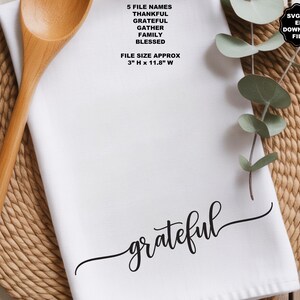 May include: A white kitchen towel featuring the black cursive text grateful. The image includes text listing 5 file names: THANKFUL, GRATEFUL, GATHER, FAMILY, BLESSED, and a file size of 3 inches H x 11.8 inches W, plus SVG PNG EPS DOWNLOAD FILES.