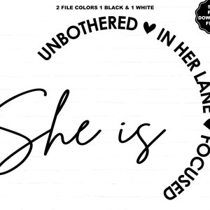 May include: Black and white graphic design with the words "She is" in a cursive font, and the phrase "Unbothered in her lane focused" in a semi-circle around the top and right side. Includes a small heart symbol.