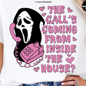 Puede incluir: Una camiseta blanca con un dise&ntilde;o gr&aacute;fico en negro y rosa. El dise&ntilde;o incluye una cara de fantasma negro sosteniendo un tel&eacute;fono rosa, con el texto "THE CALL'S COMING FROM INSIDE THE HOUSE?" en rosa. Tambi&eacute;n incluye corazones rosas.