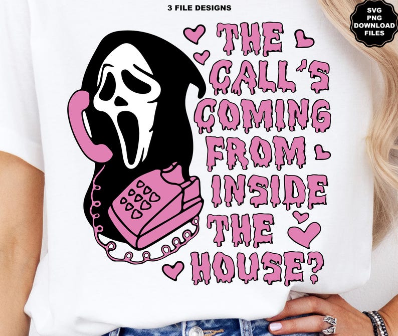 Puede incluir: Una camiseta blanca con un dise&ntilde;o gr&aacute;fico en negro y rosa. El dise&ntilde;o incluye una cara de fantasma negro sosteniendo un tel&eacute;fono rosa, con el texto "THE CALL'S COMING FROM INSIDE THE HOUSE?" en rosa. Tambi&eacute;n incluye corazones rosas.