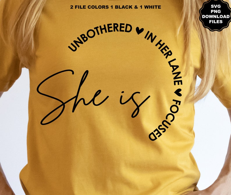 May include: Mustard yellow t-shirt with black text. The shirt features the words "UNBOTHERED IN HER LANE FOCUSED" in a curved design, with the words "She is" in a cursive font. The top also includes the text "2 FILE COLORS 1 BLACK & 1 WHITE" and "SVG PNG DOWNLOAD FILES".