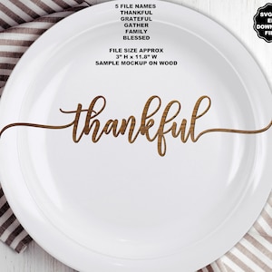 May include: A white plate featuring the word thankful in a brown wood grain script font. Text above reads 5 FILE NAMES THANKFUL GRATEFUL GATHER FAMILY BLESSED FILE SIZE APPROX 3" H x 11.8" W SAMPLE MOCKUP ON WOOD. A black badge reads SVG PNG EPS DOWNLOAD FILES.