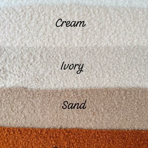 Może przedstawiać: Pięć pr&oacute;bek tkaniny w r&oacute;żnych odcieniach bieli, kremu, kości słoniowej, piasku i rdzawej pomarańczy. Pr&oacute;bki są ułożone pionowo od najjaśniejszego do najciemniejszego.