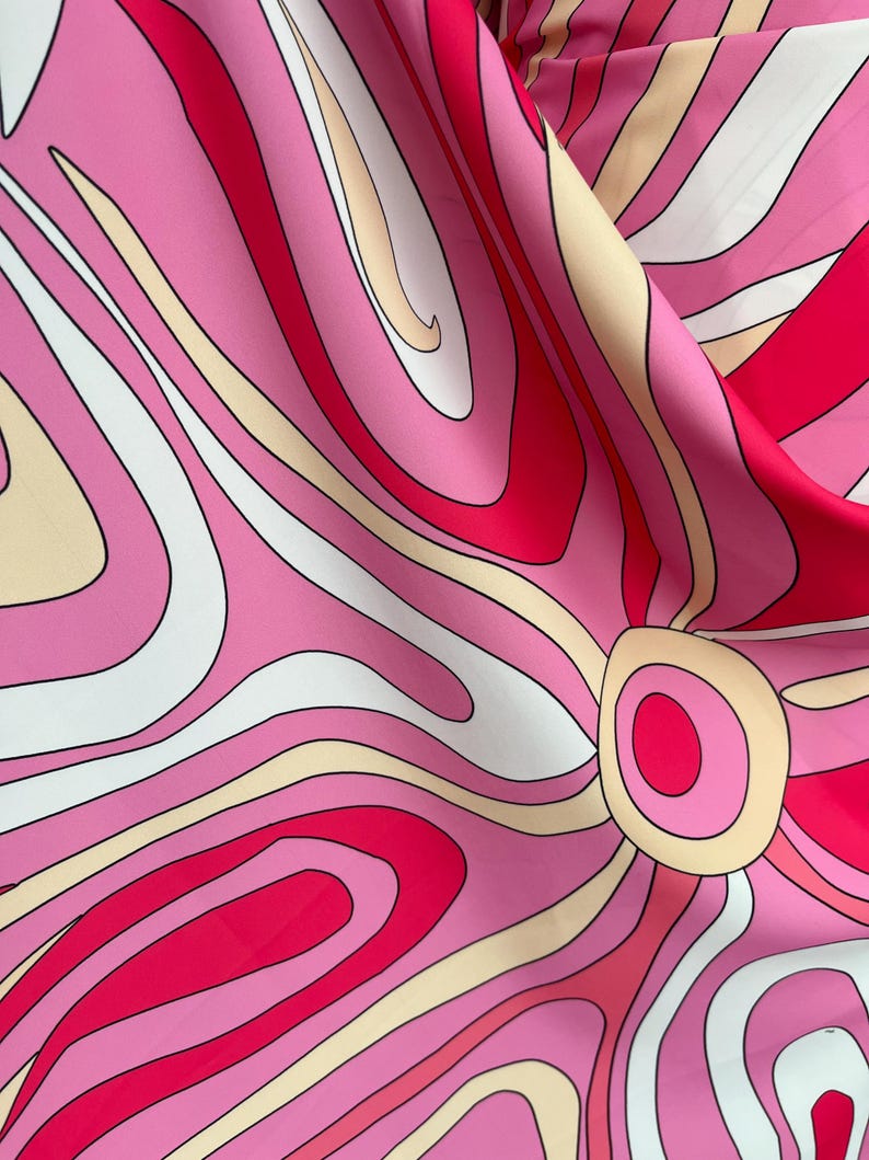 Puede incluir: Primer plano de una tela con un dise&ntilde;o retro y psicod&eacute;lico. El patr&oacute;n presenta l&iacute;neas arremolinadas en tonos de rosa, rojo, blanco y beige, creando un efecto visual vibrante y llamativo. El dise&ntilde;o se asemeja a una flor estilizada.