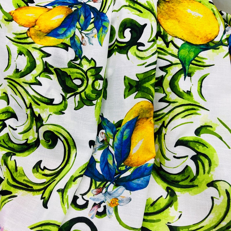 Puede incluir: Tela blanca con un dise&ntilde;o de acuarela de limones amarillos, hojas azules y follaje verde. La tela presenta un patr&oacute;n repetido de limones y adornos decorativos, creando una est&eacute;tica fresca y veraniega. Ideal para la decoraci&oacute;n del hogar o la ropa.