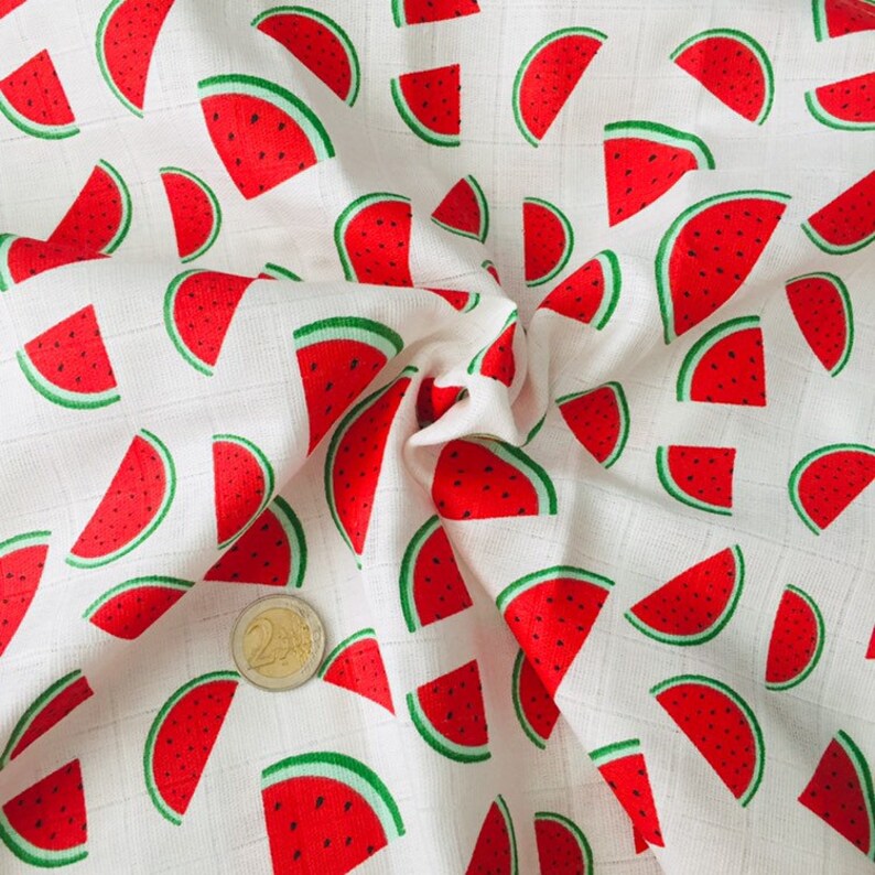 May include: White fabric with a repeating pattern of red watermelon slices. The fabric is textured and has a subtle grid pattern.
