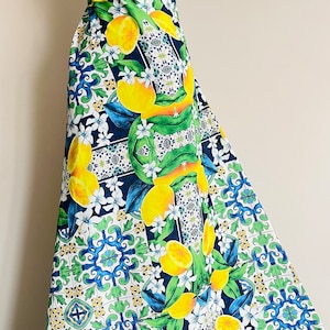 May include: A white fabric with a colorful lemon and tile pattern. The fabric features yellow lemons, green leaves, blue and white tiles, and a white background.