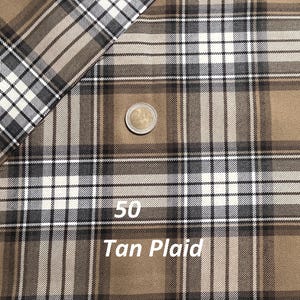 May include: A tan plaid fabric featuring a pattern of intersecting dark brown and white lines. A two-euro coin is placed on the fabric for scale, and a wooden ruler at the bottom shows measurements in inches, with the fabric width spanning seven inches.