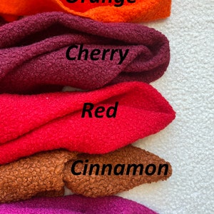 Może przedstawiać: Pięć pr&oacute;bek tkaniny w r&oacute;żnych odcieniach czerwieni, pomarańczy i brązu. Pr&oacute;bki są oznaczone jako "Pomarańczowy", "Wiśniowy", "Czerwony", "Cynamonowy" i "Malinowy".