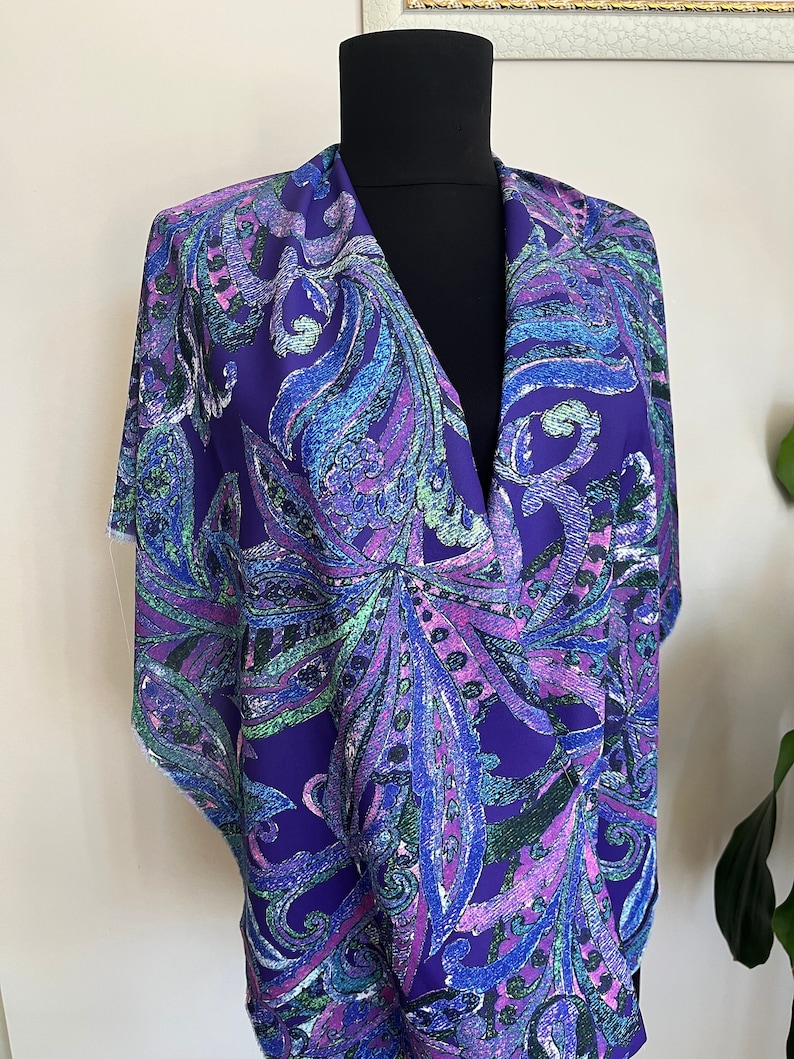 May include: A purple scarf with a paisley pattern in shades of blue, green, and pink.